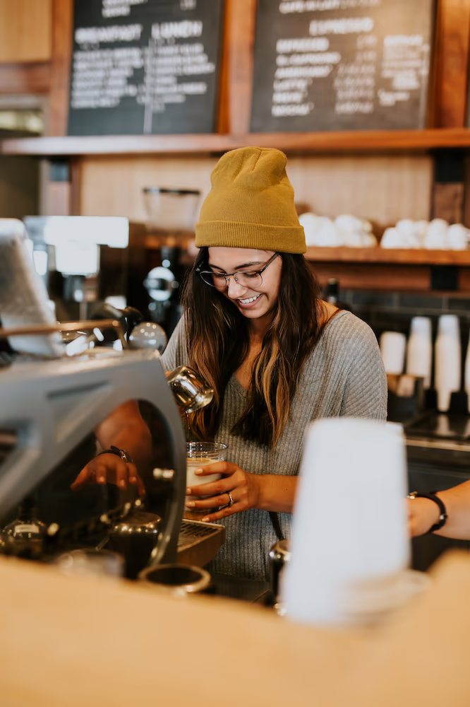 Smiling female barista making coffee for a customer.